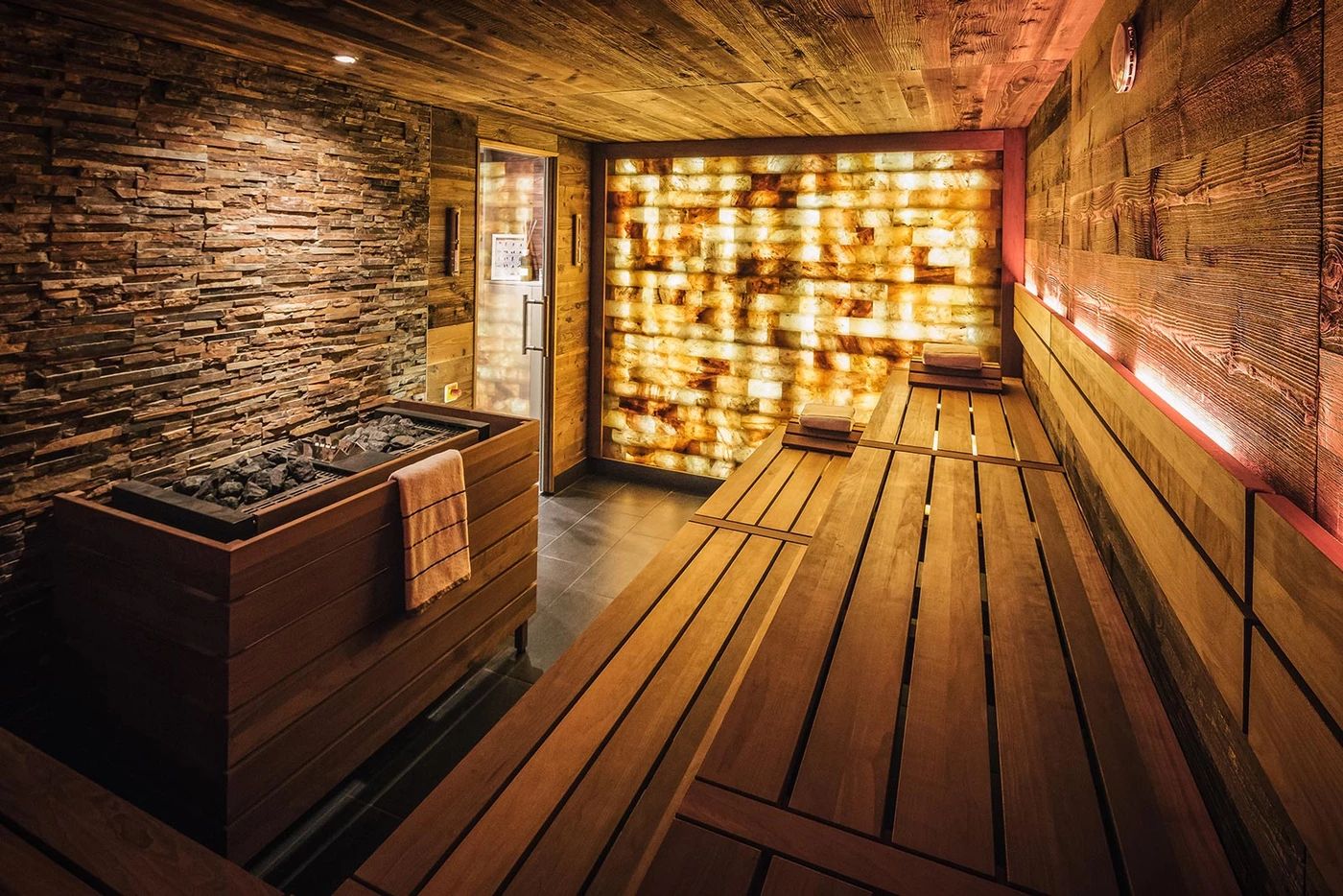 Sauna au sel avec mur lumineux et bancs en bois.