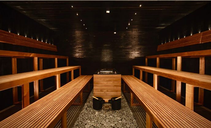 Grand sauna en bois avec poêle central.